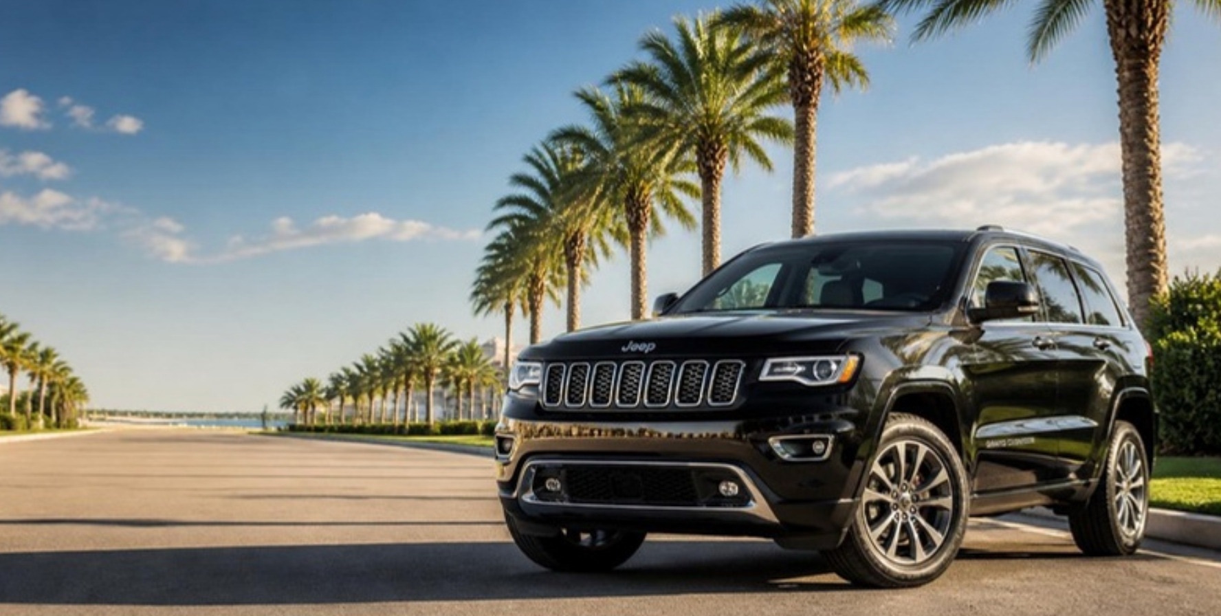 Jeep Grand Cherokee preto em avenida com palmeiras